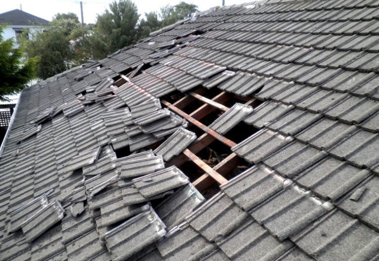 Severely storm-damaged tile roof with exposed underlying structure