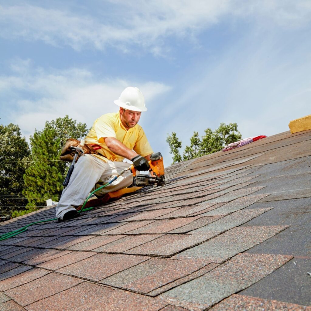 Roofing contractor installing asphalt shingles on a residential roof